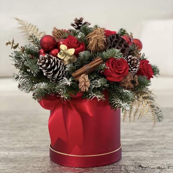 Red roses and pinecones arranged in a red gift box