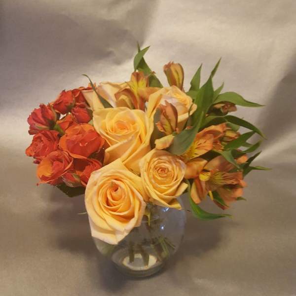 Bouquet of peach and orange roses in a clear glass vase