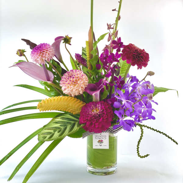 Colorful mixed bouquet in a glass vase with orchids and dahlias