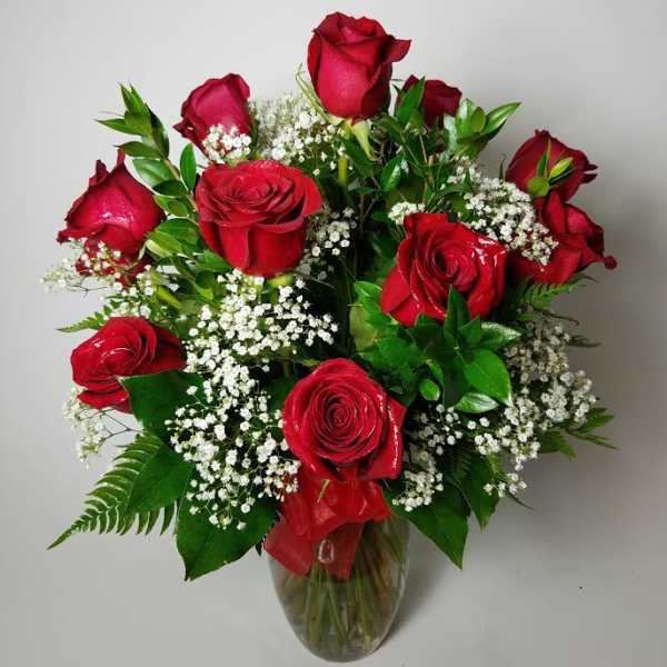 Red roses arranged in a clear glass vase with white filler flowers