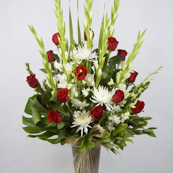 Red roses and white flowers in a tall gray vase
