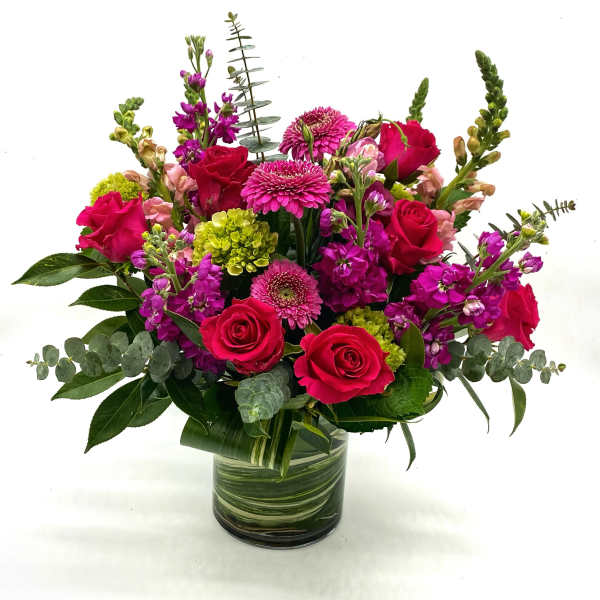 Bouquet of pink roses and magenta flowers in a glass vase