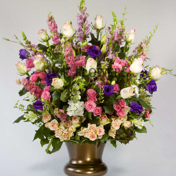 Large mixed bouquet of pink, white, and purple flowers in a bronze vase