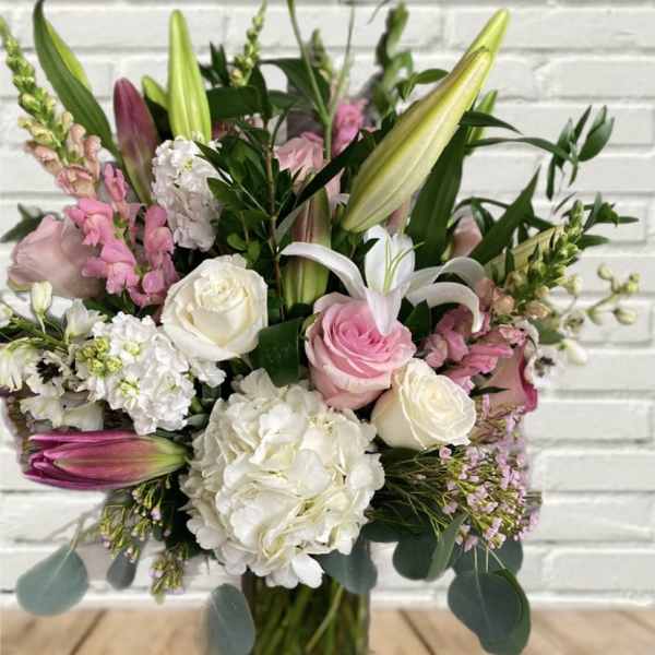 Pink and white bouquet with lilies and roses in a glass vase
