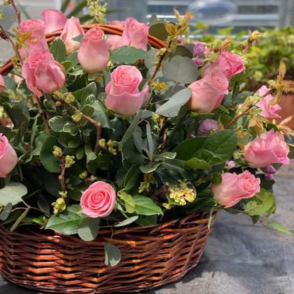 Pink roses arranged in a wicker basket.