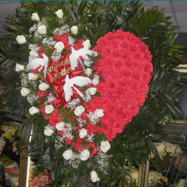 Heart-shaped floral tribute with red carnations and white roses
