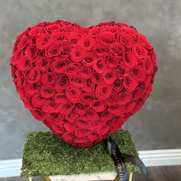Heart-shaped arrangement of red roses on a moss-covered base