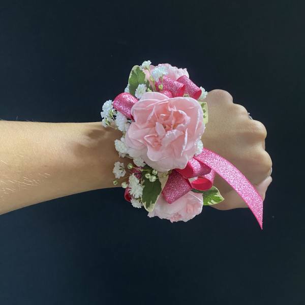 Pink floral wrist corsage with ribbon on a person's wrist