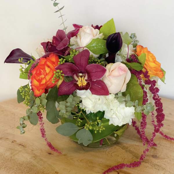 Mixed bouquet with roses, orchids, and white blooms in a glass vase