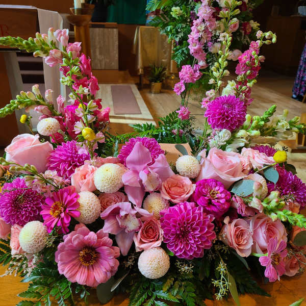Pink floral arrangement with roses, dahlias, and snapdragons on a table