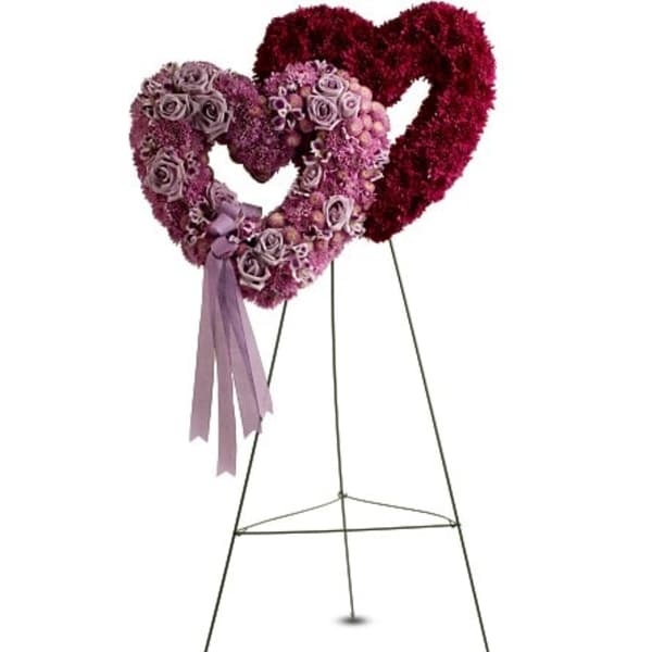 Two heart-shaped floral stands with pink and burgundy flowers on metal easels