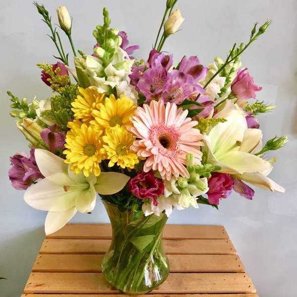 Mixed bouquet of pink, yellow, and white flowers in a glass vase