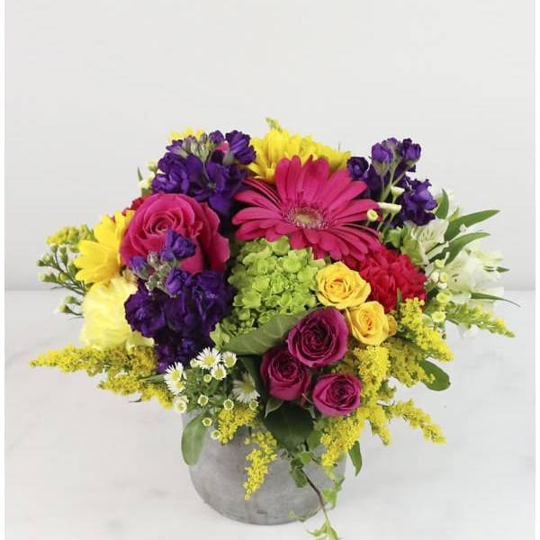 Colorful bouquet of roses, gerbera daisies, and mixed blooms in a gray vase