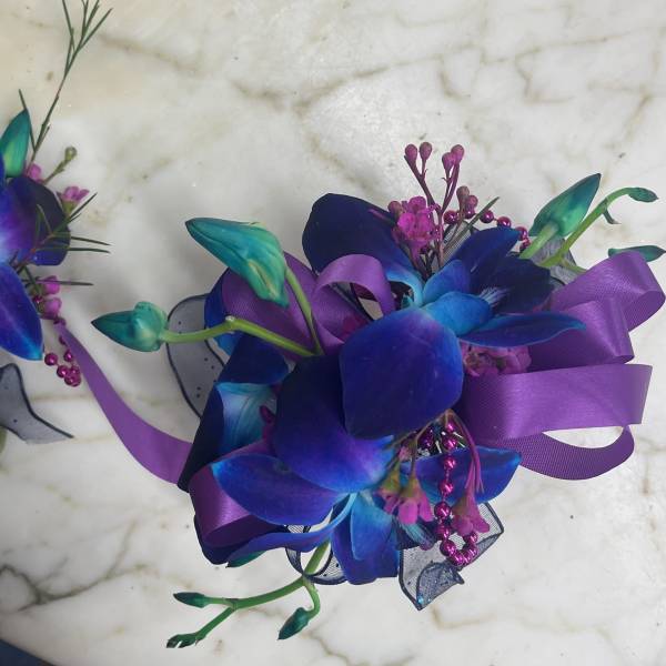 Two purple and blue orchid corsages with ribbon accents