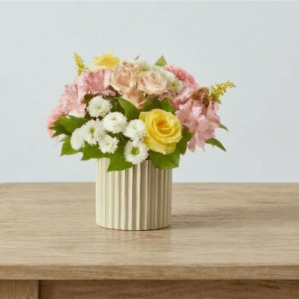 Pink and yellow flower arrangement in a ribbed vase