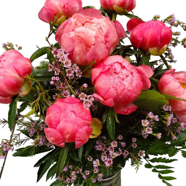 Pink peonies arranged in a glass vase with small purple filler flowers