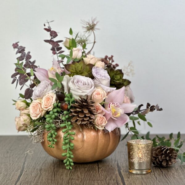 Floral arrangement in a copper pumpkin container with roses and orchids