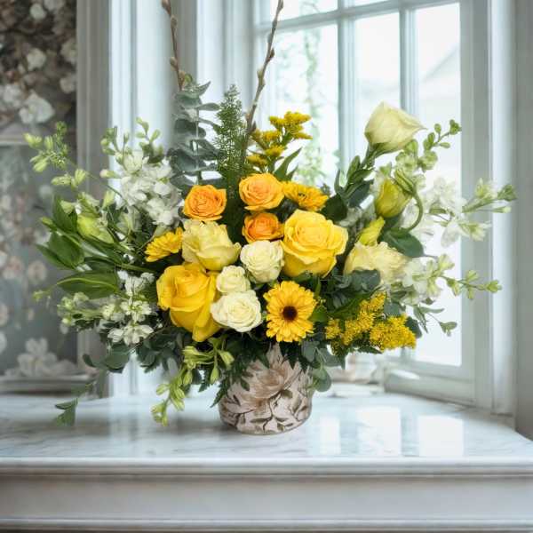 Yellow and white floral arrangement in a floral-print vase