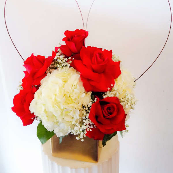 Red roses and white hydrangeas in a gold box with heart wire accents