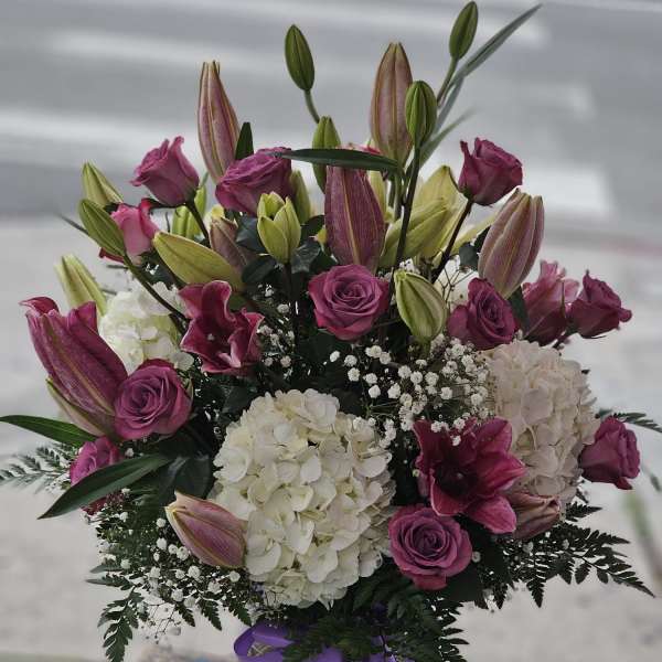 Bouquet of pink roses, lilies, and white hydrangeas in a glass vase