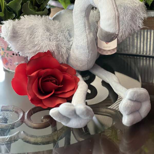 Plush flamingo with a red rose and potted flowering plant