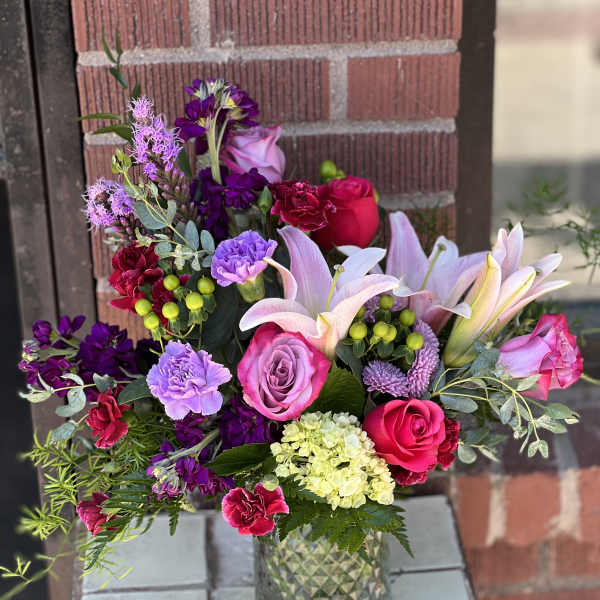 Mixed bouquet of pink, purple, and white flowers in a glass vase