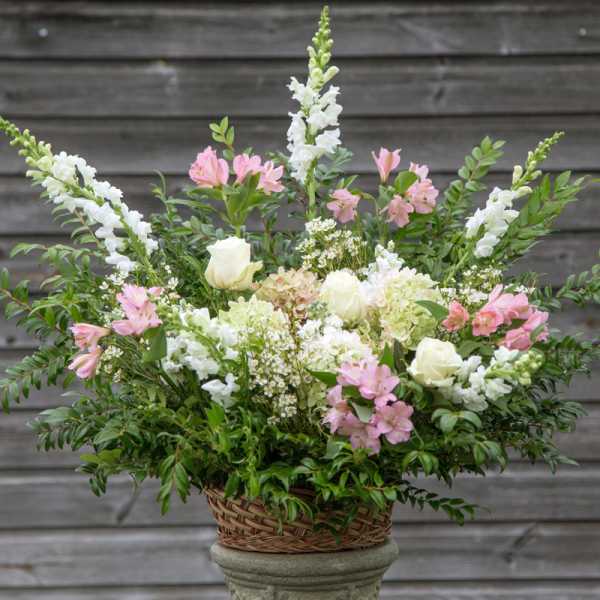 Basket arrangement of white roses, pink alstroemeria, and white snapdragons