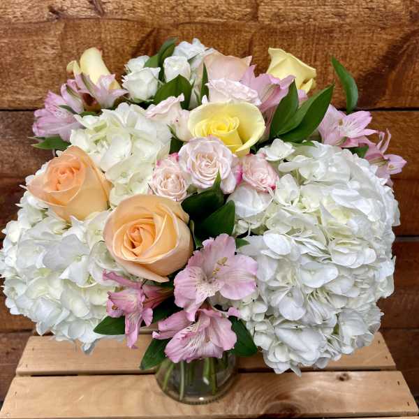 Bouquet of pastel roses, hydrangeas, and pink alstroemeria in a glass vase