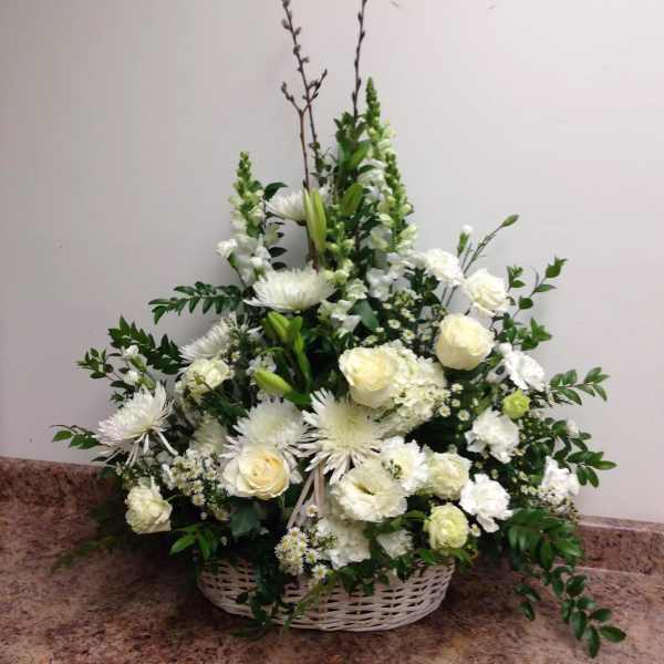 White floral arrangement in a wicker basket with roses and lilies