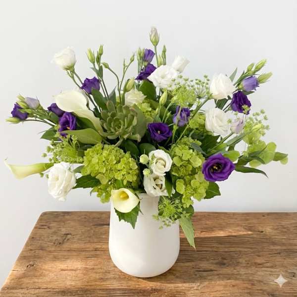 White and purple flowers arranged in a white vase