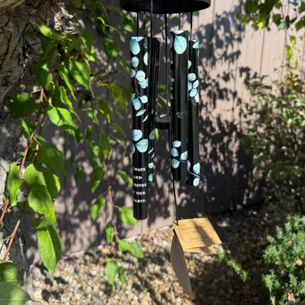 Black memorial wind chime hanging outdoors with blue leaf accents