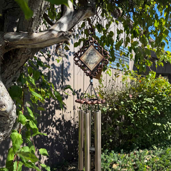 Decorative wind chime hanging from a tree branch outdoors