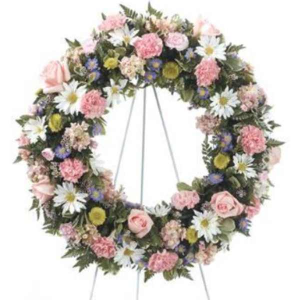 Circular floral wreath on a stand with pink and white flowers
