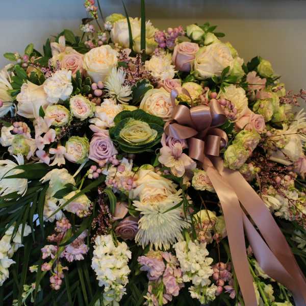 Large pastel floral arrangement with roses, daisies, and a satin ribbon