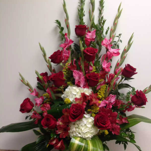 Tall red rose and pink flower arrangement in a white vase