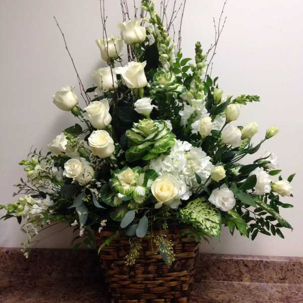 White roses and hydrangeas in a wicker basket arrangement