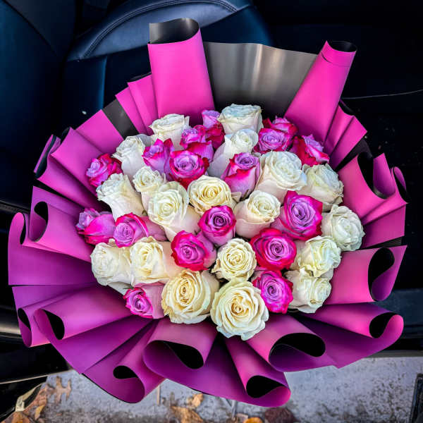Bouquet of pink, white, and lavender roses wrapped in bright magenta paper