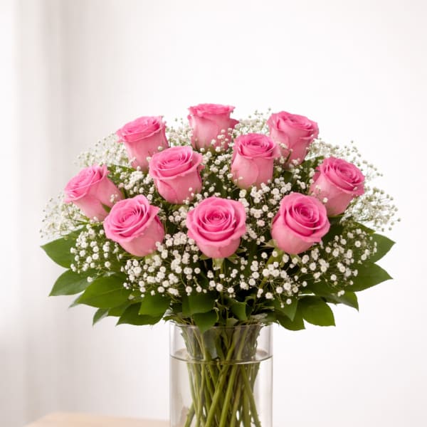Pink roses arranged in a clear glass vase with white filler flowers