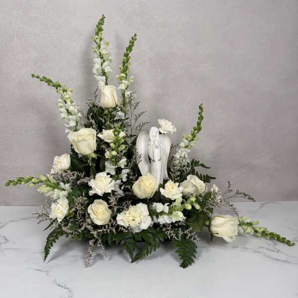 White floral arrangement with roses, snapdragons, and an angel figurine