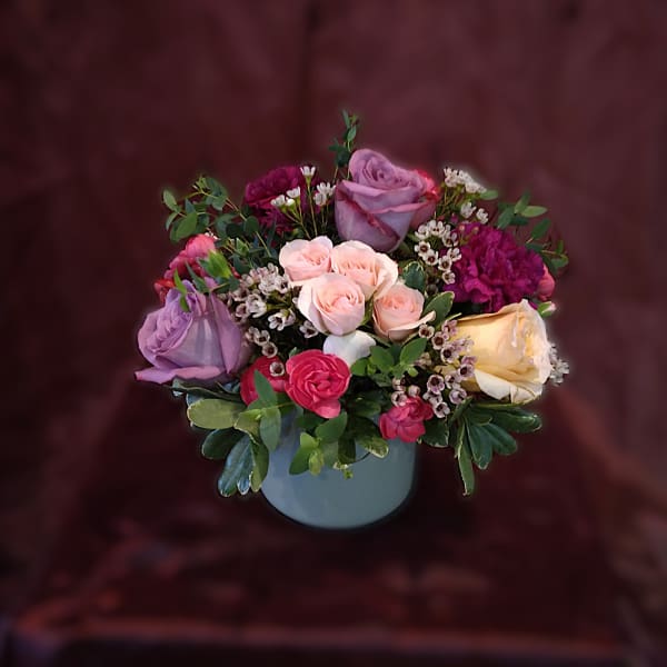 Mixed roses and small white filler flowers in a blue vase