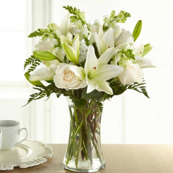 White lilies and roses arranged in a clear glass vase
