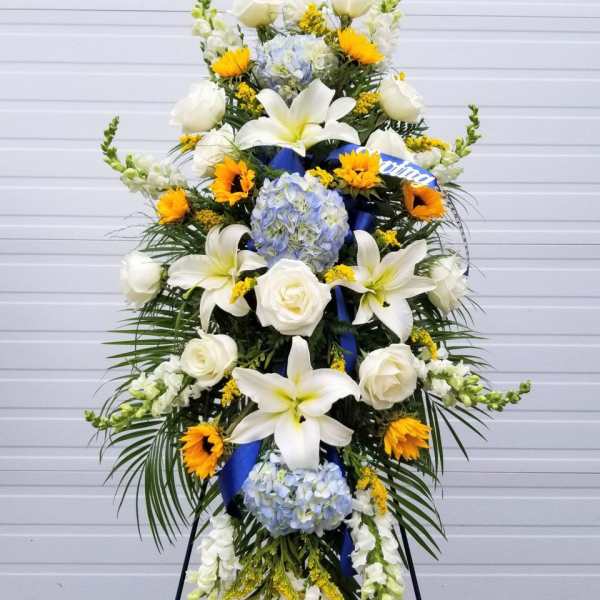 Tall standing floral spray with white lilies, roses, hydrangeas, and sunflowers