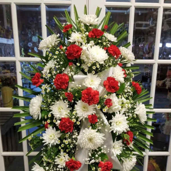 Standing floral spray with red and white flowers on a white ribbon