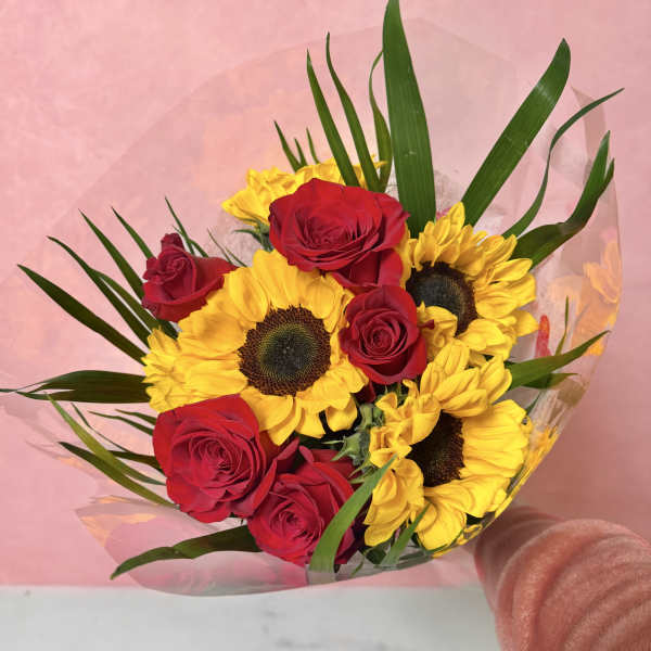 Bouquet of red roses and yellow sunflowers wrapped in pink paper