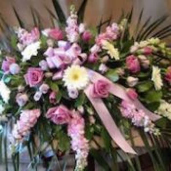 Pink and white sympathy spray with roses, daisies, and ribbon in an elongated design