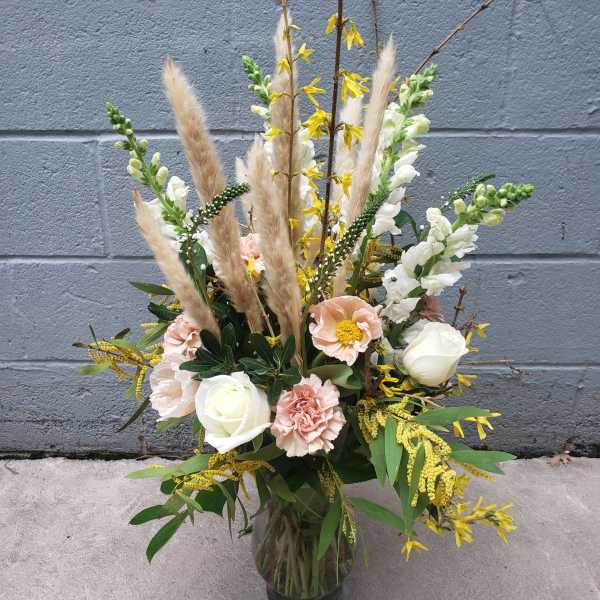 Tall bouquet of white and blush flowers in a glass vase