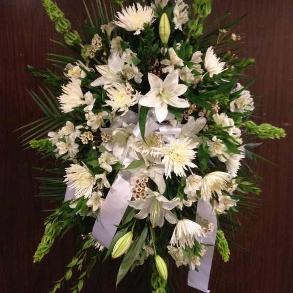 White funeral spray with lilies, chrysanthemums, and ribbon