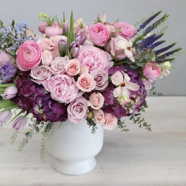 Pink and purple mixed flower arrangement in a white vase