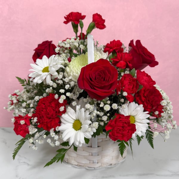 Basket arrangement of red roses, carnations, and white daisies