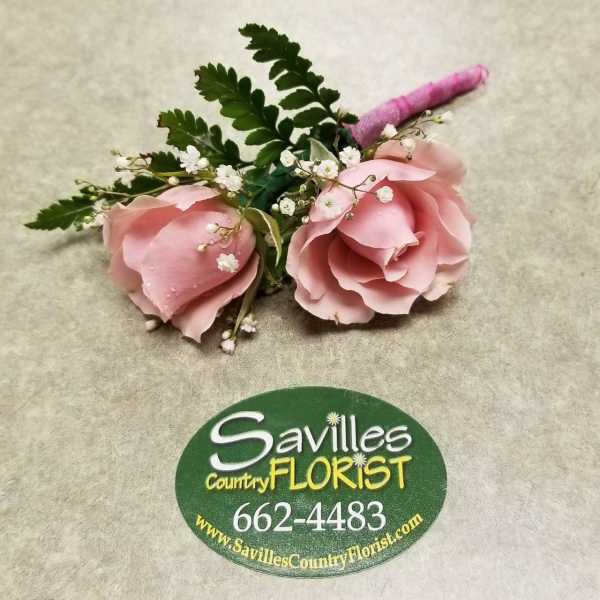 Two pink rose boutonnieres with baby's breath and greenery